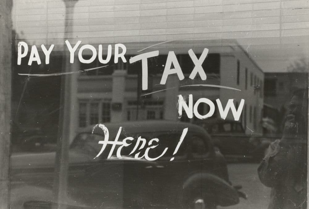 Fensterscheibe mit der Aufschrift: Pay your tax now here